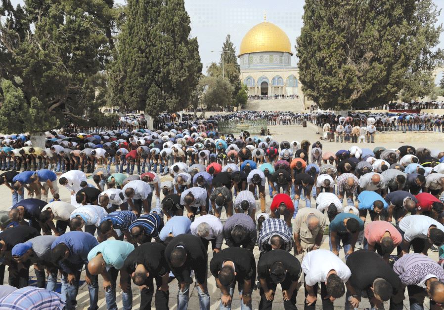 THE DOME of the Rock is seen in the background as Palestinian men take part in Friday prayers in Jerusalem.