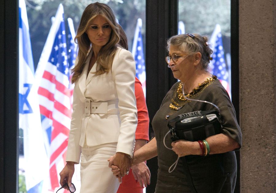 US first lady Melania Trump (L) holds the hand of Nechama Reuven, wife of Israeli president Reuven Rivlin, as they walk near American flags at Rivlin's residence in Jerusalem May 22, 2017