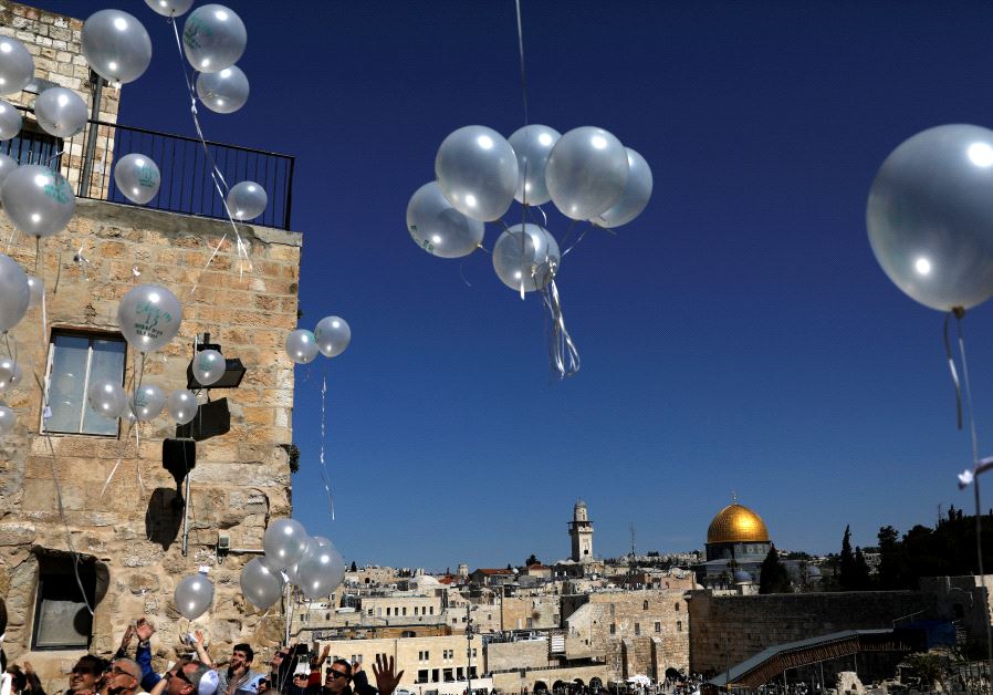 People release balloons as they celebrate a Bar Mitzva as the Western Wall and the Dome of the Rock are seen in the background, in Jerusalem's Old City