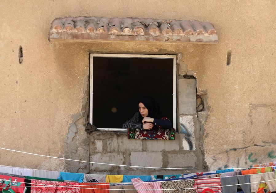 A WOMAN looks out a window in the Gaza Strip