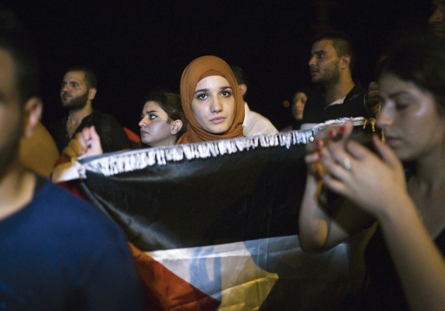 A woman holds a Palestinian flag as she attends a protest in support of a hunger-striking Palestinian prisoner in 2015 in Ashkelon