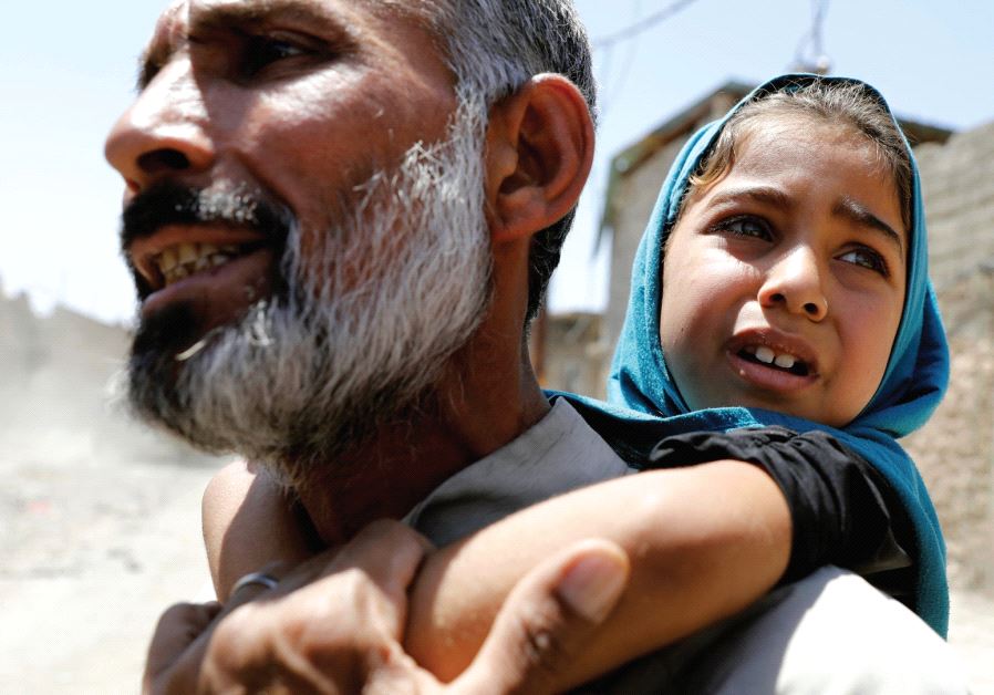 A MAN carries his daughter on his back after fleeing their home due to fighting between Iraqi forces and Islamic State fighters in Mosul’s al-Zanjili district in Iraq