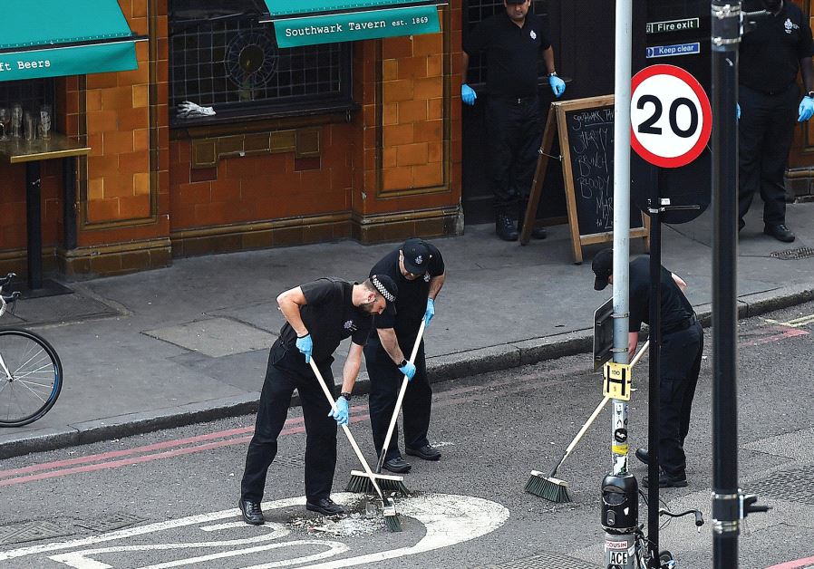POLICE OFFICERS sweep the street outside a restaurant in Borough Market, near the scene of the recent attack in London