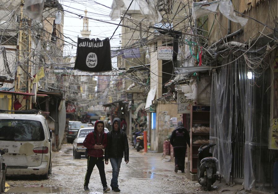 Youth walk under an Islamic State flag in Ain al-Hilweh Palestinian refugee camp, near the port-city of Sidon, southern Lebanon January 19, 2016.