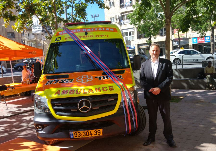  Dov Maisel poses Sunday next to the first mobile intensive care unit in Israel, dedicated in his uncle, Allen Beer’s, memory