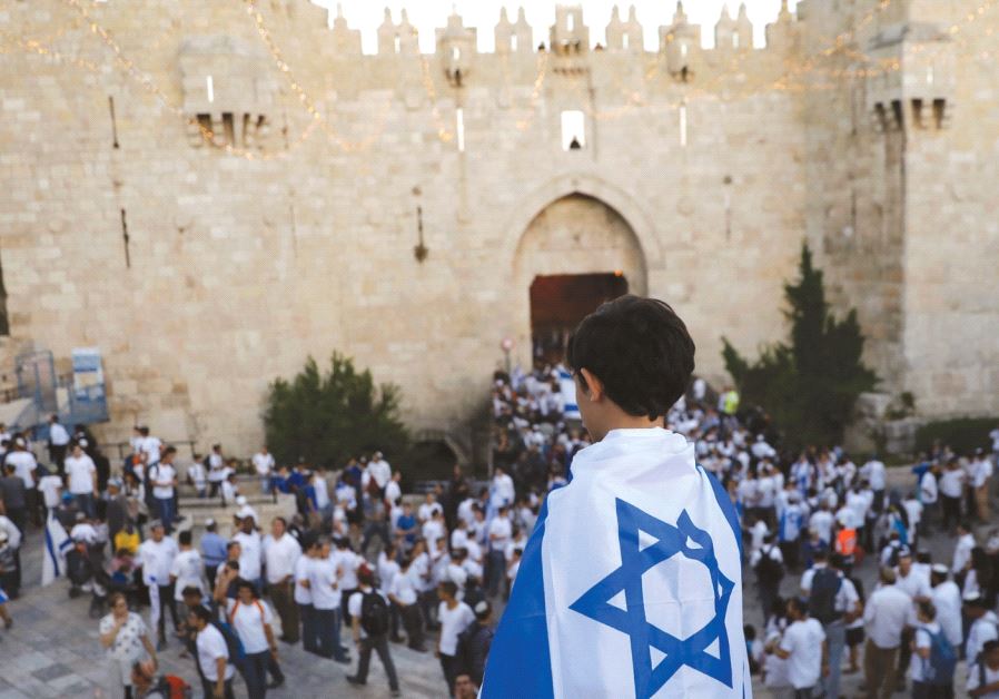 A BOY wrapped with Israel’s national flag is seen during a parade marking Jerusalem Day last month outside the Old City Walls. Israel, the author argues, needs to assert more sovereignty