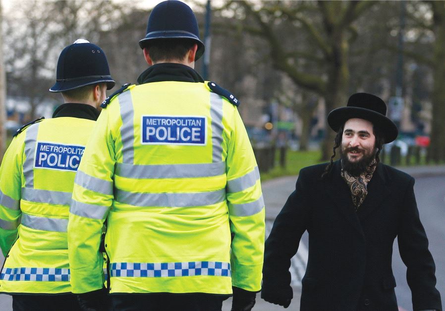 A MEMBER of the Jewish community walks in north London in 2015 as police officials stand watch.