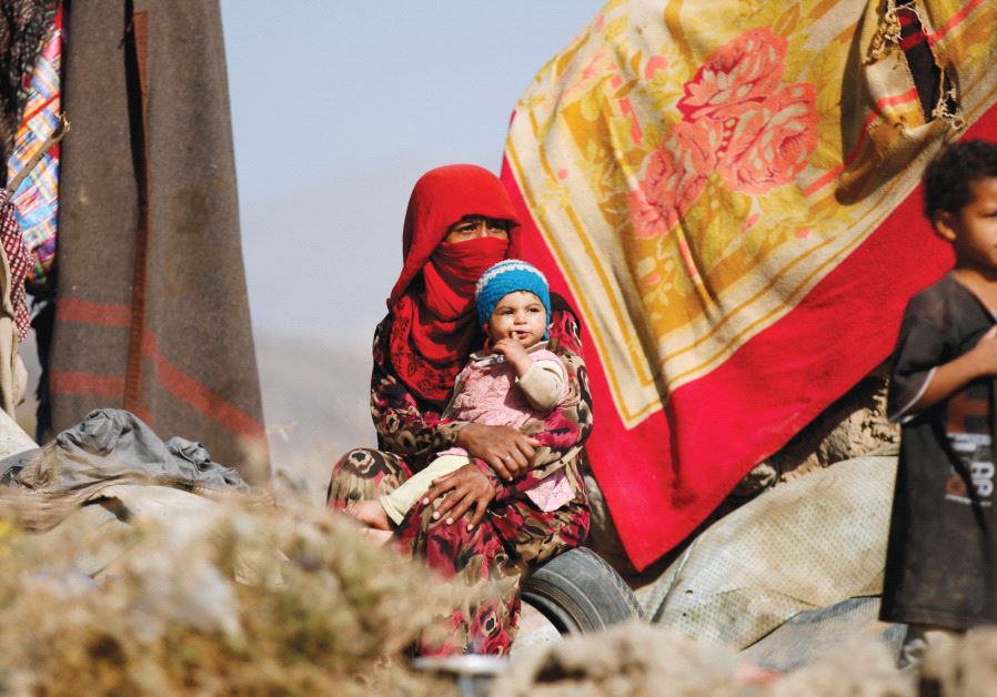 A WOMAN sits with her children near their tent at a camp for internally displaced people in Dharawan, near the Yemenite capital of Sanaa.