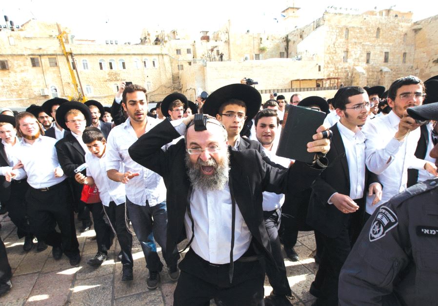 An ultra-Orthodox Jewish man holds a Bible as he protests against a monthly prayer session of the Women of the Wall group at the Western Wall, 2013