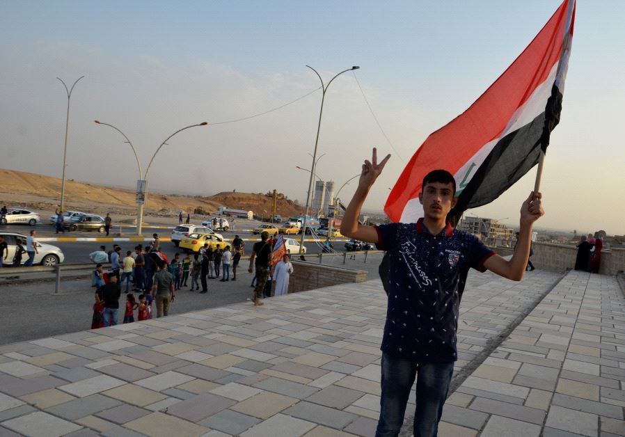 An Iraqi man waves his naitonal flag in the newly liberated city of Mosul, July 9