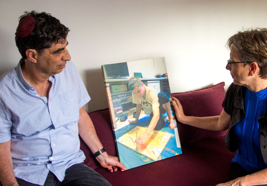 Simha and Leah Goldin with a   photo of Hadar doing one of the activities he loved - painting - his last piece before he was killed.
