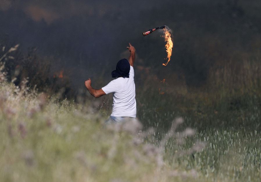 A Palestinian protester hurls a molotov cocktail towards Israeli troops during clashes at a protest in support of Palestinian prisoners on hunger strike in Israeli jails, near the Jewish settlement of Beit El, near the West Bank city of Ramallah May 11, 2017.