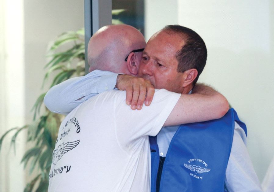 Avi Balashnikov is embraced by Jerusalem Mayor Nir Barkat at a ceremony on the first anniversary of the death of Balashnikov’s wife, Revital Yahalomi-Balashnikov.