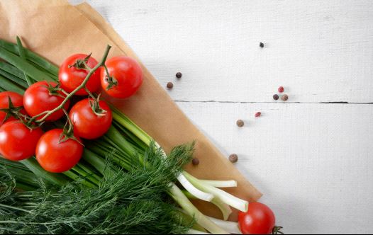 Fresh organic vegetable set of tomatoes dill and onion on white kitchen table