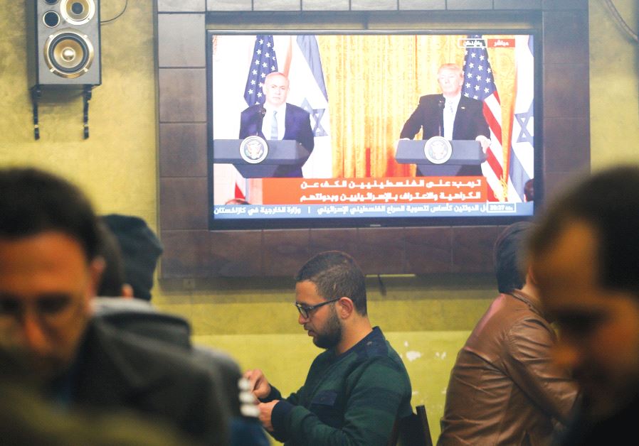 PALESTINIANS GATHER in a coffee ship in Hebron, where a TV screen shows US President Donald Trump and Prime Minister Benjamin Netanyahu participating in a joint press conference in February.