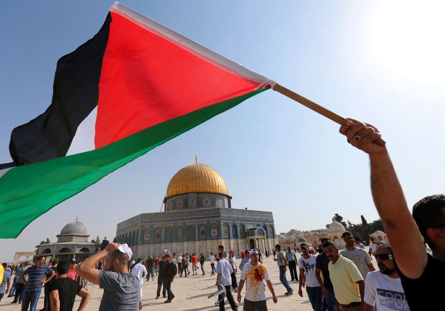 The Dome of the Rock is seen in the background as a man waves a Palestinian flag upon entering the Temple Mount, after Israel removed all security measures it had installed at the compound, in Jerusalem's Old City July 27, 2017.