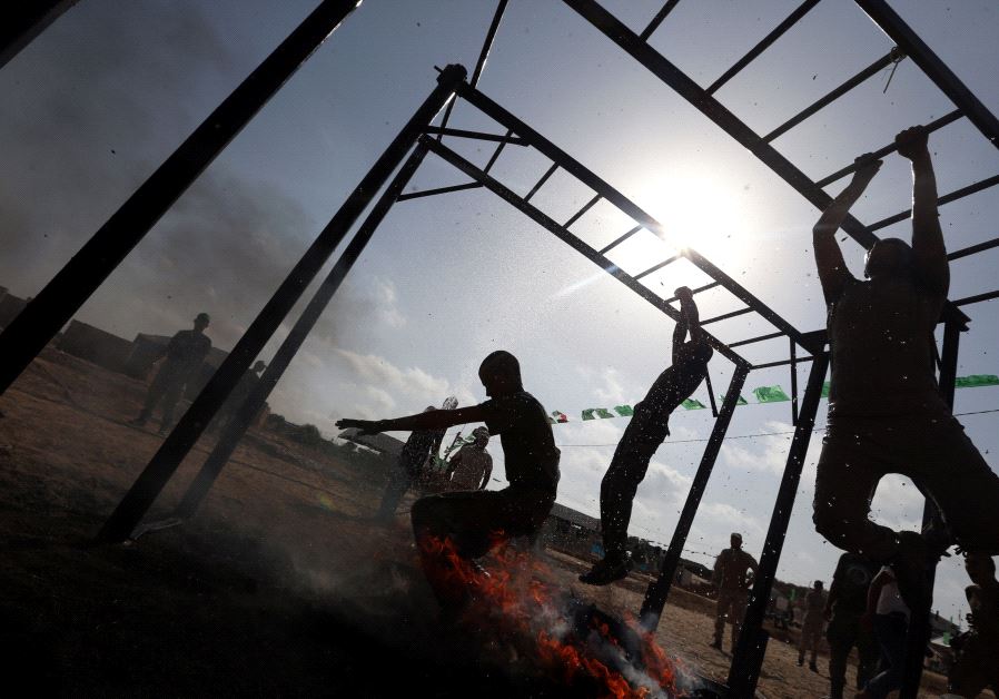 Young Palestinians swing across monkey bars over fire during a military-style exercise at a Hamas summer camp in Rafah in the southern Gaza Strip July 27, 2017. 